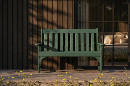 Dark green bench on a wooden deck with a blurred background