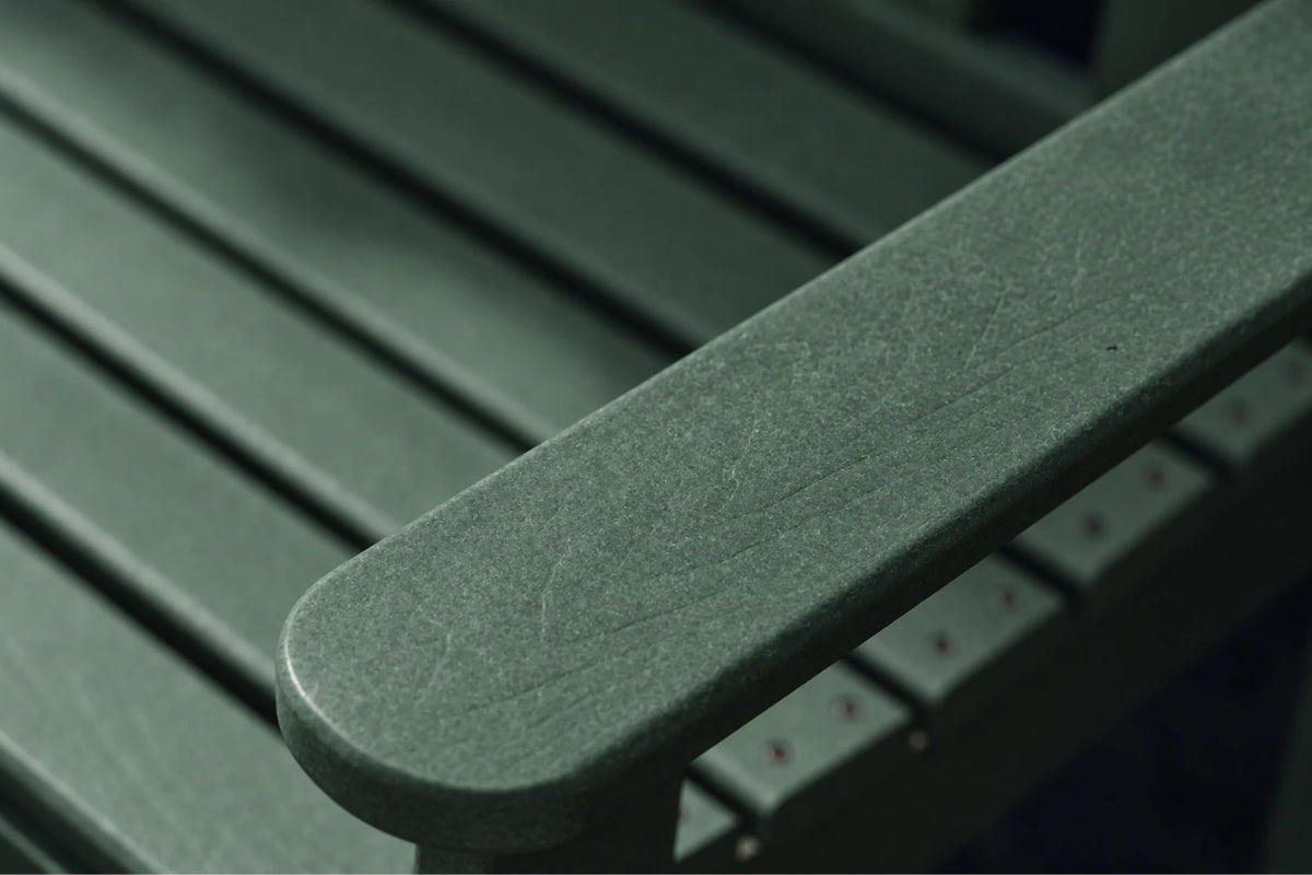 Close-up of a dark green slatted outdoor bench armrest with a textured finish, showing the curved end and parallel slats in the background.