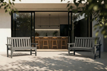 Two gray benches in a modern outdoor setting with a kitchen in the background.