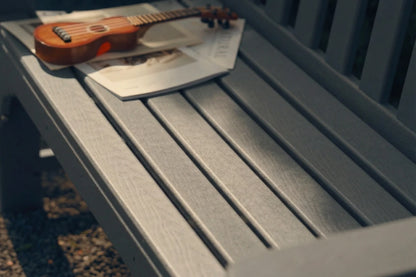 Small wooden guitar on a gray bench with a blurred background