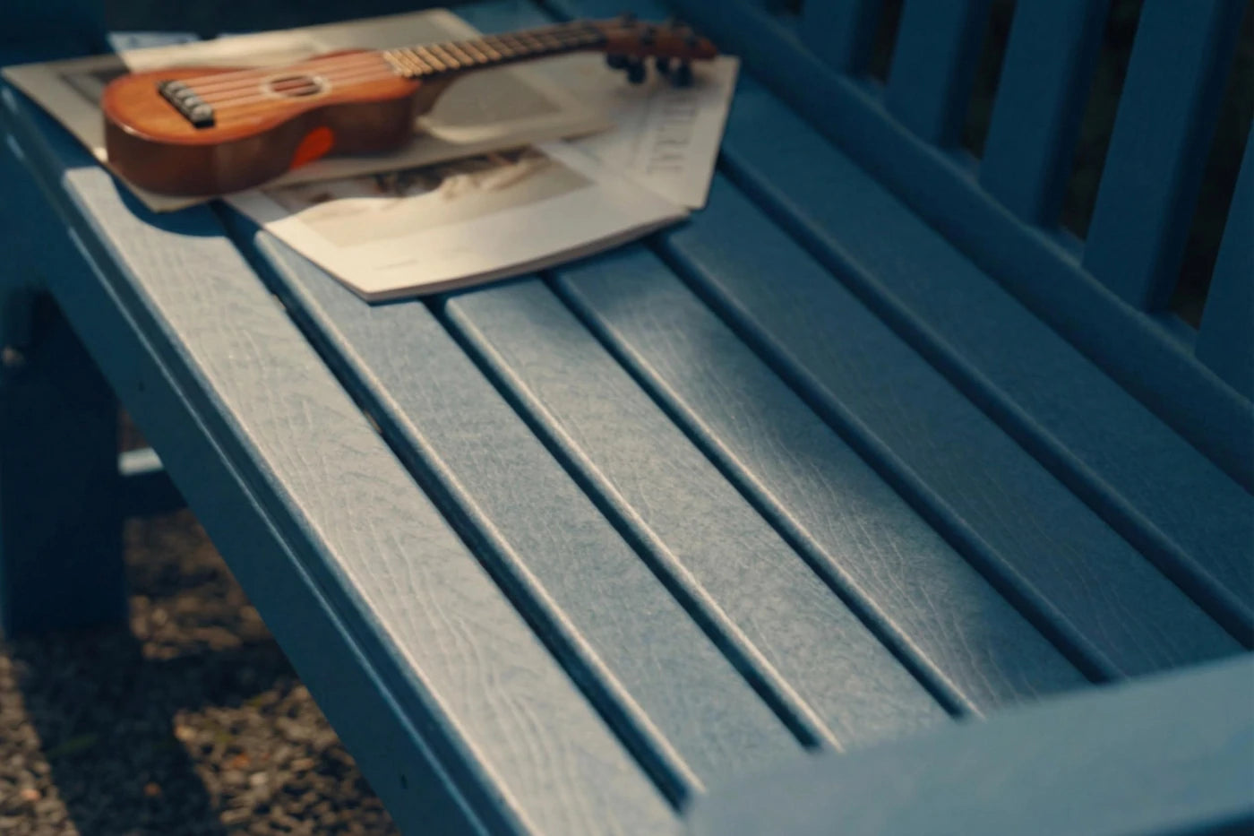 Small guitar and newspaper on a blue bench