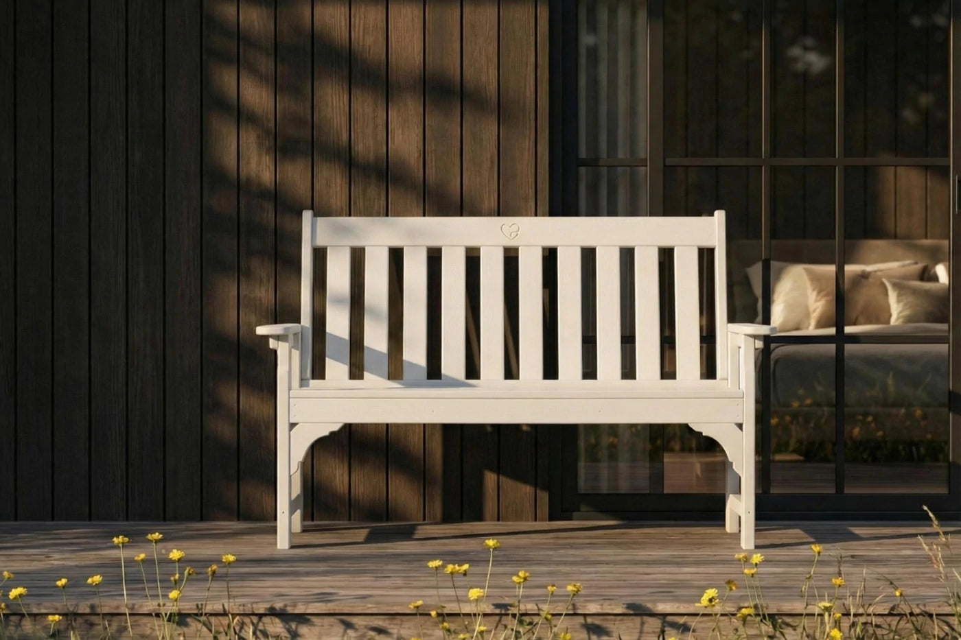 White bench on a wooden deck with a dark wooden wall and glass door in the background.