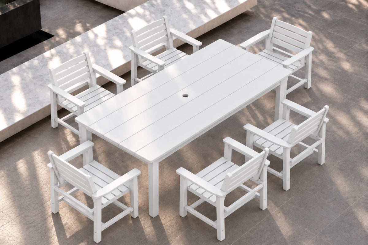 White outdoor dining set consisting of a rectangular slatted table and six matching armchairs, shown on a paved patio with natural dappled shadows.