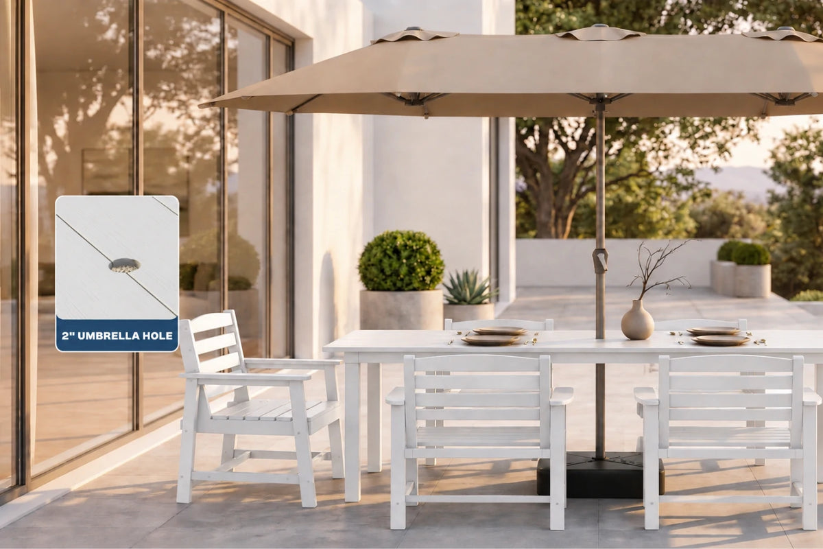 Outdoor patio dining setup with a white slatted table and chairs under a large beige patio umbrella, with a glass-walled building in the background. A callout box on the left highlights the umbrella hole design.