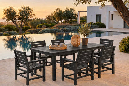 A 7-piece outdoor dining set consisting of a rectangular slatted table and six matching armchairs in black, styled on a stone patio next to an infinity pool at sunset.
