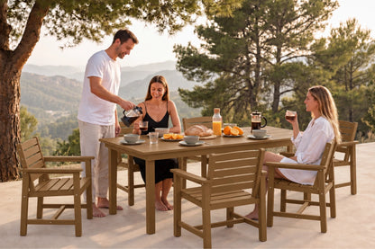 A outdoor dining set with four chairs and a rectangular table, shown in use by three people on a patio with a scenic mountain background at sunset.