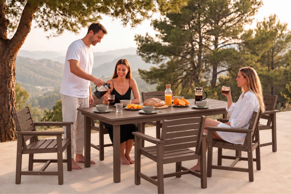 A 7-piece outdoor dining set with a rectangular wooden table and six matching slatted chairs, shown in use with three people having a meal on a patio with a scenic mountain background.