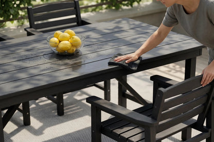 Person cleaning a wooden outdoor table with lemons on it