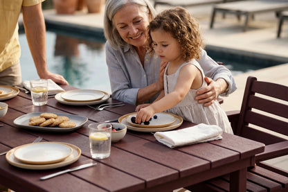 Woman and child at an outdoor dining table by a poolside
