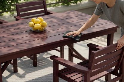 Person cleaning a wooden outdoor table with lemons on it