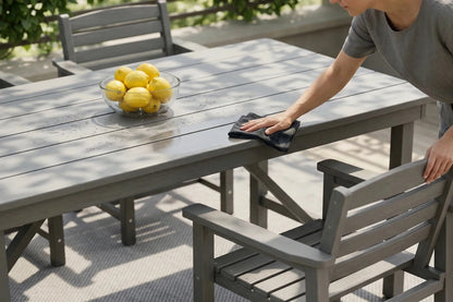 Person cleaning an outdoor table with lemons and a bowl on it