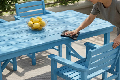 Person cleaning a blue outdoor table with lemons in the background