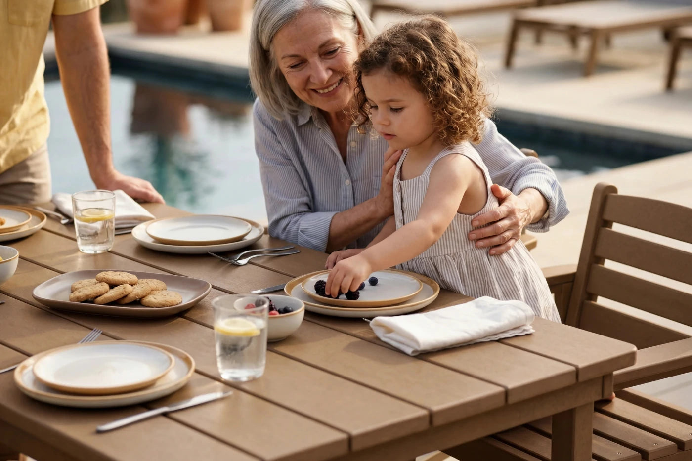 Woman and child at an outdoor dining table by a poolside