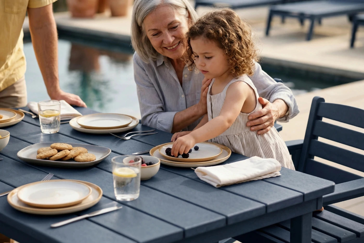 Woman and child at an outdoor dining table by a poolside
