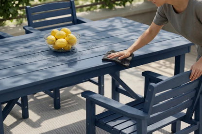 Person cleaning a blue outdoor table with lemons in the background