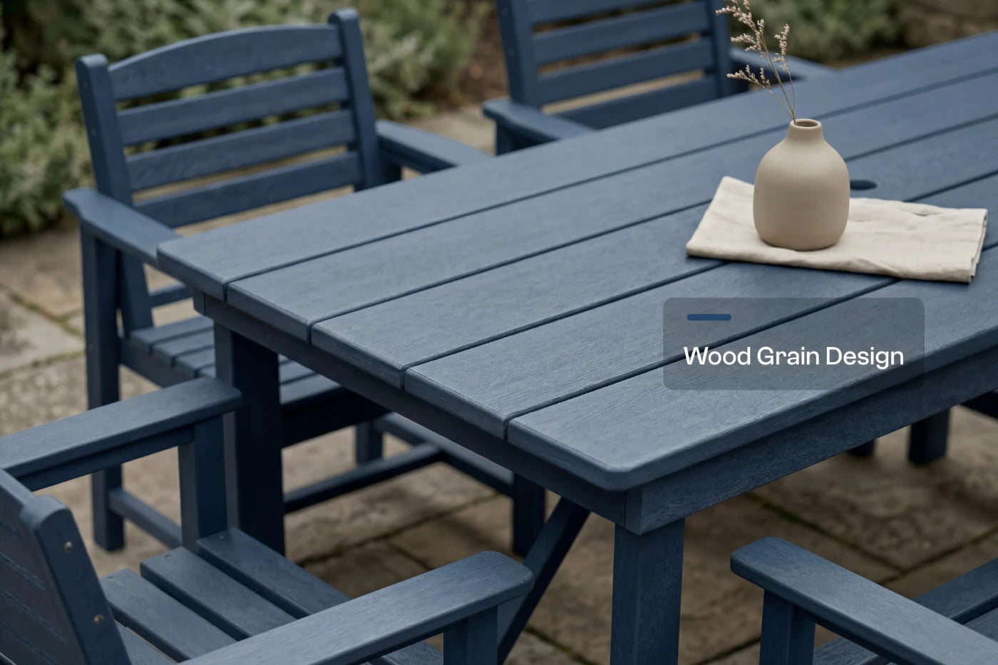 Blue outdoor dining table with chairs and a vase on a patio