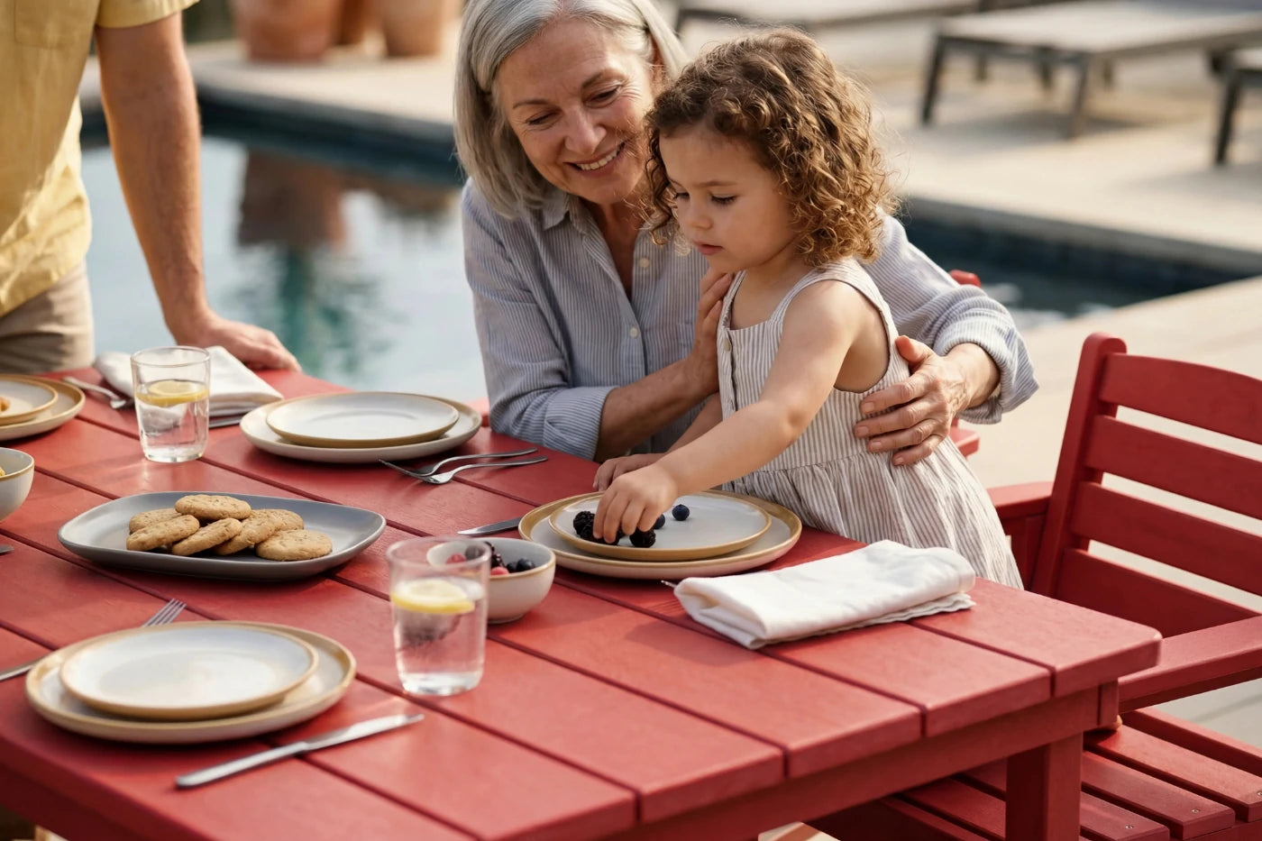 Woman and child at a dining table outdoors by a pool