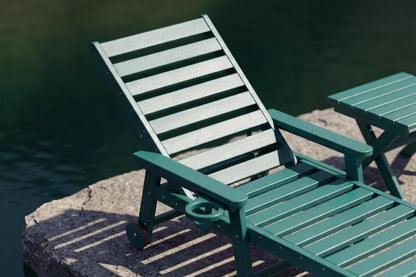 Two green lounge chairs by a body of water.