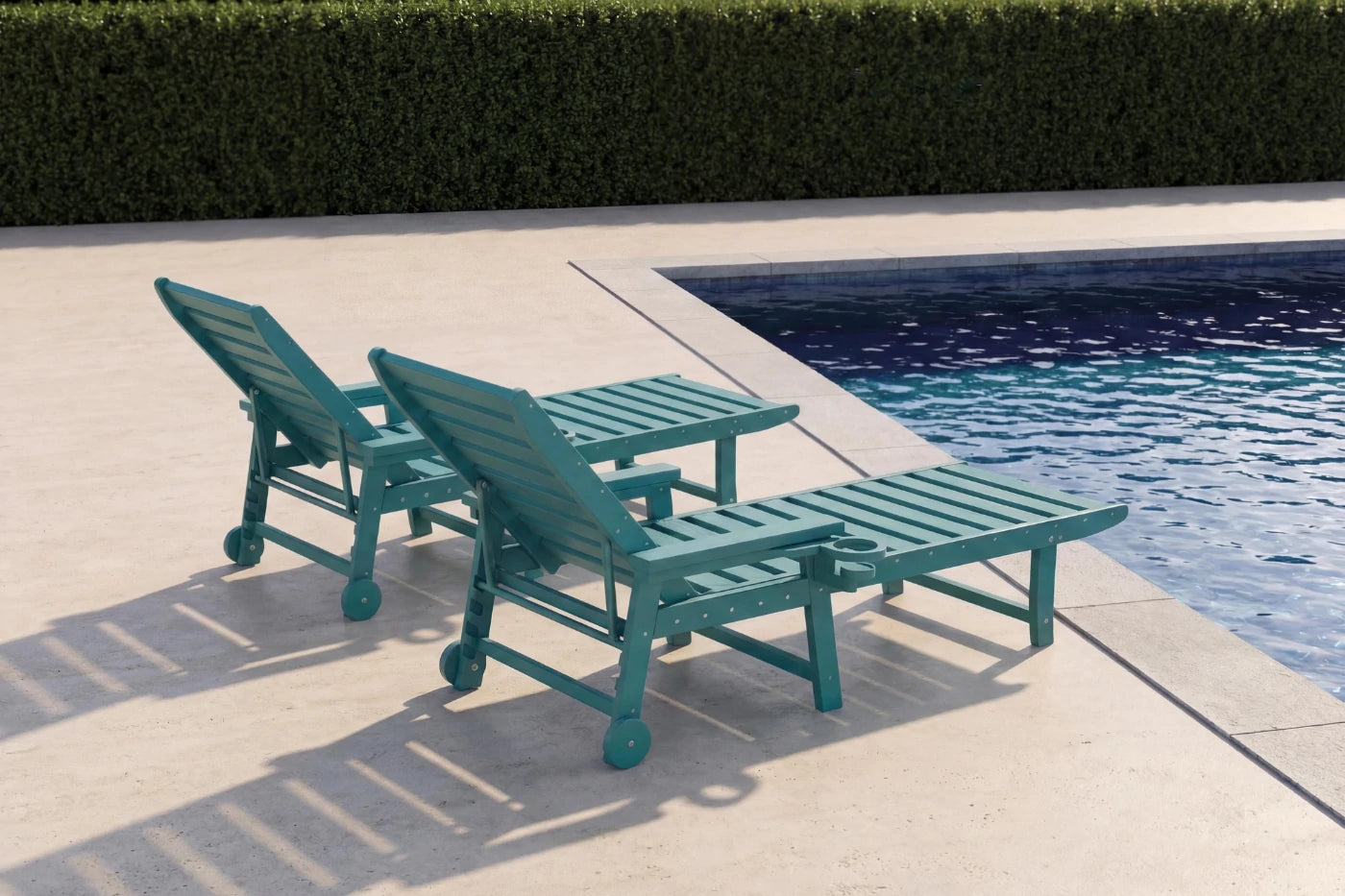 Two teal lounge chairs by a poolside with a hedge in the background
