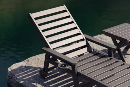 Gray lounge chair and table by a body of water