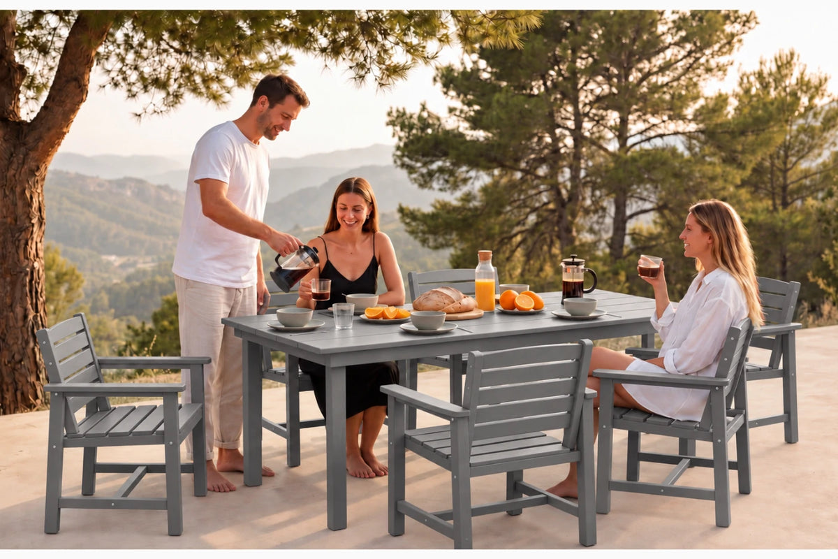 A gray outdoor patio dining set with a rectangular table and six slatted chairs, shown in use by three people having a meal on a sunny terrace with a mountain landscape in the background.