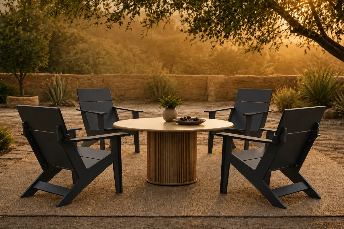 Four black outdoor Adirondack-style chairs arranged around a round light wood dining table with a ribbed pedestal base, set on a patio in a warm, golden evening outdoor scene.