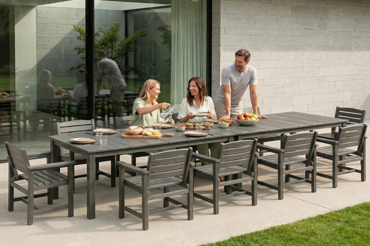 Family of four enjoying a meal outdoors at a long gray dining table with chairs.