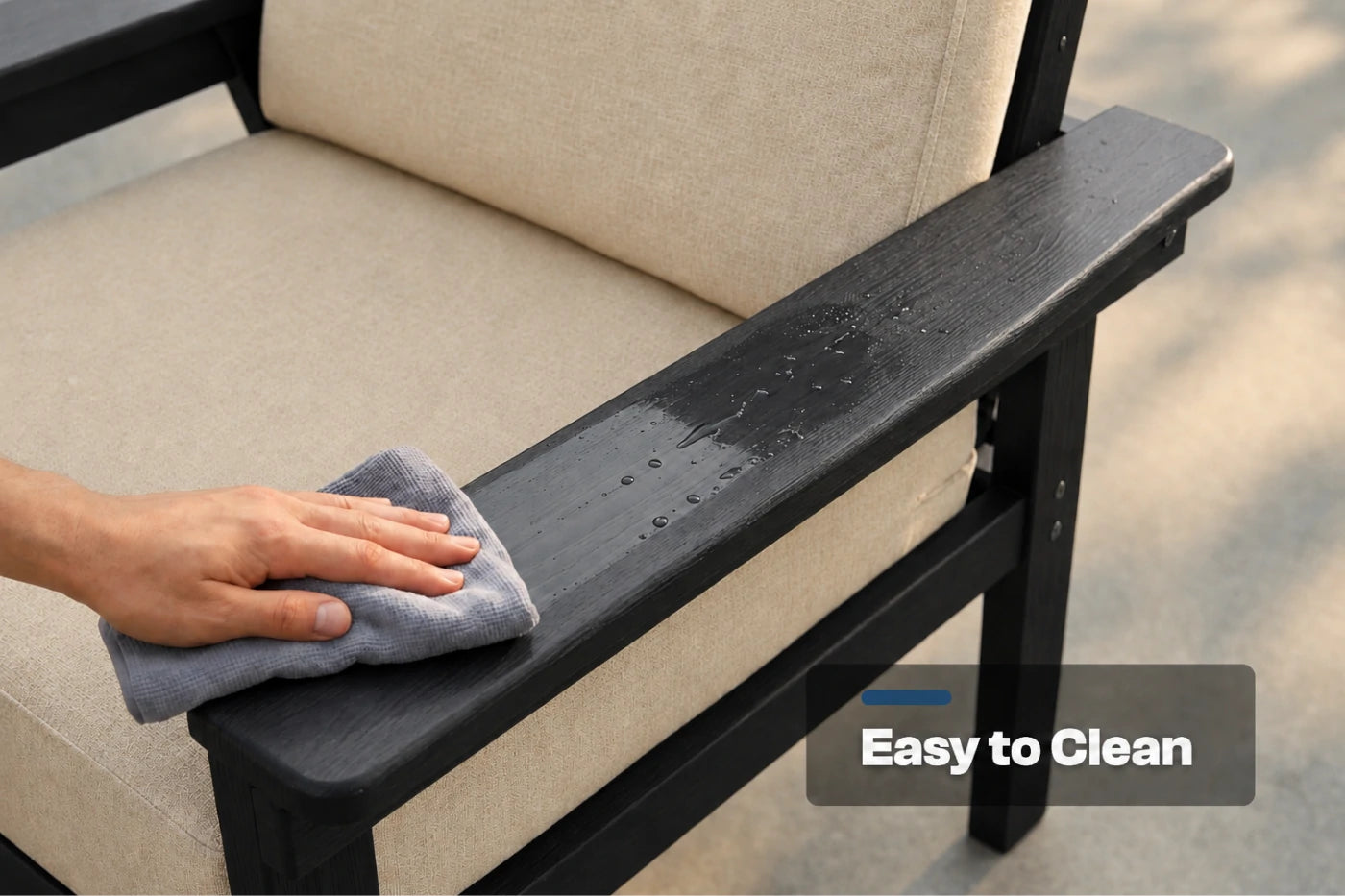 A close-up of a hand wiping down a black armrest of an outdoor chair with a gray cloth, with creamy white cushions. A text overlay reads 'Easy to Clean'.