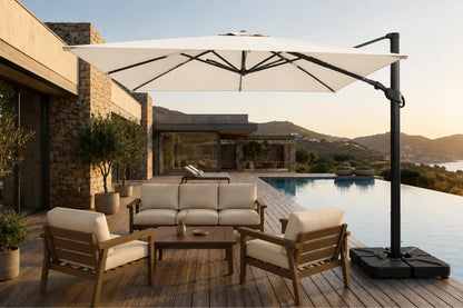 A large creamy white cantilever patio umbrella with a black pole and base, shading a modern outdoor lounge set with wooden chairs and a sofa on a wooden deck beside a swimming pool.