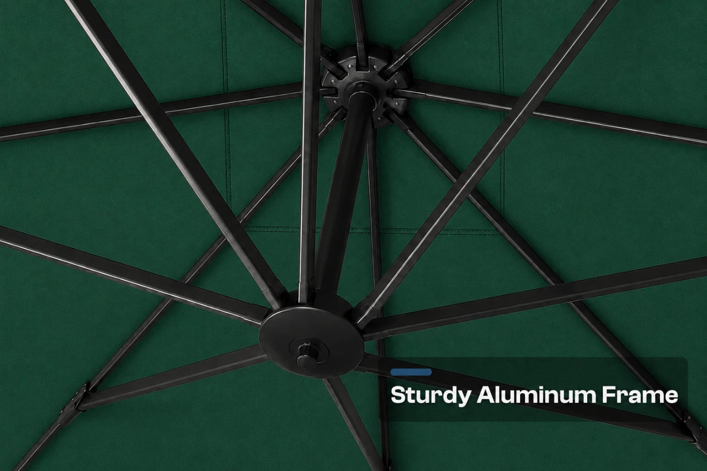 Close-up of a dark green patio umbrella canopy showing the black aluminum frame ribs radiating from the center, with a text overlay that reads 'Sturdy Aluminum Frame'.