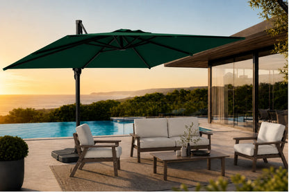 A large dark green patio umbrella shading a modern outdoor seating area with a pool and ocean view at sunset.