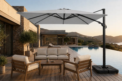 A large cantilever patio umbrella in a modern outdoor lounge setting next to a swimming pool, with a wooden deck, outdoor sofa, chairs, and a house in the background.