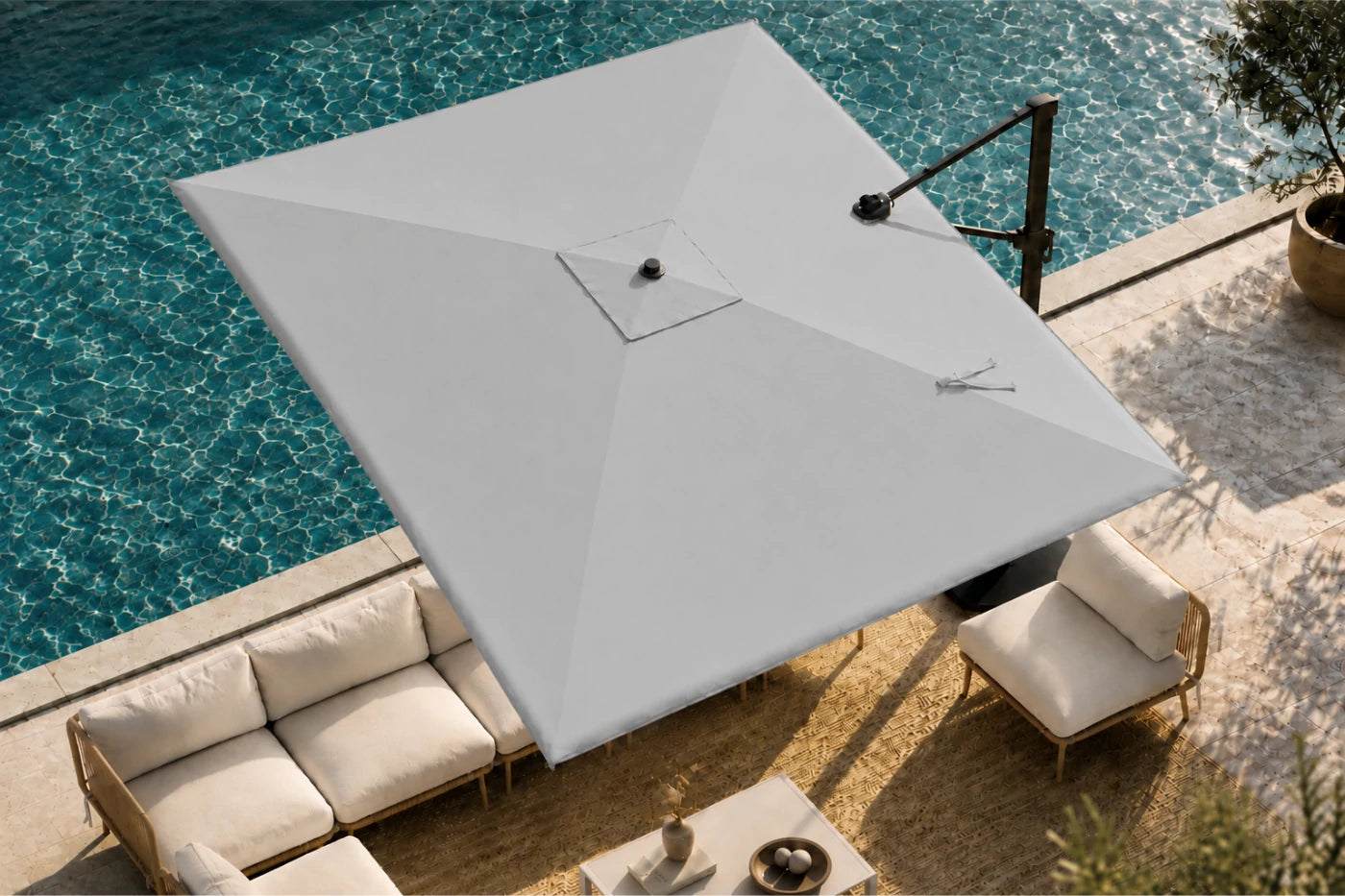 A large patio umbrella in a gray fabric shade, shown in a real outdoor poolside setting with lounge chairs, a sofa, and a stone deck.