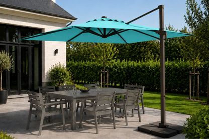 A large turquoise cantilever patio umbrella with a dark metal pole and base, shading a gray outdoor dining table and chairs on a patio next to a house.