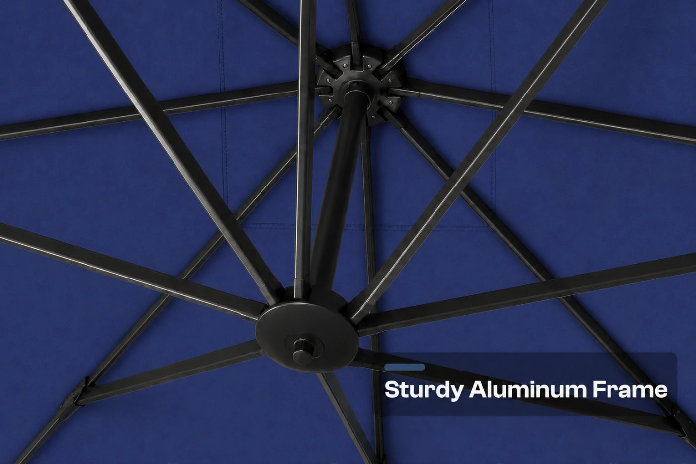 Close-up of the underside of a navy blue patio umbrella showing the black aluminum canopy frame and spokes, with a text overlay reading 'Sturdy Aluminum Frame'.