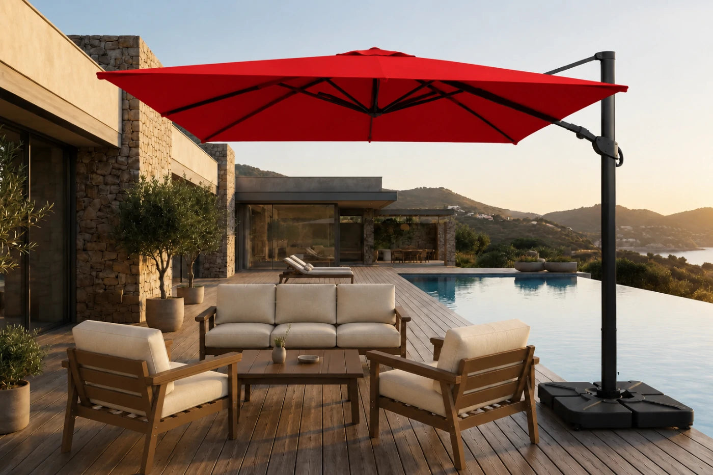 A large red cantilever patio umbrella with a black pole and base, shading a modern outdoor lounge set with beige cushions on a wooden deck beside a swimming pool.