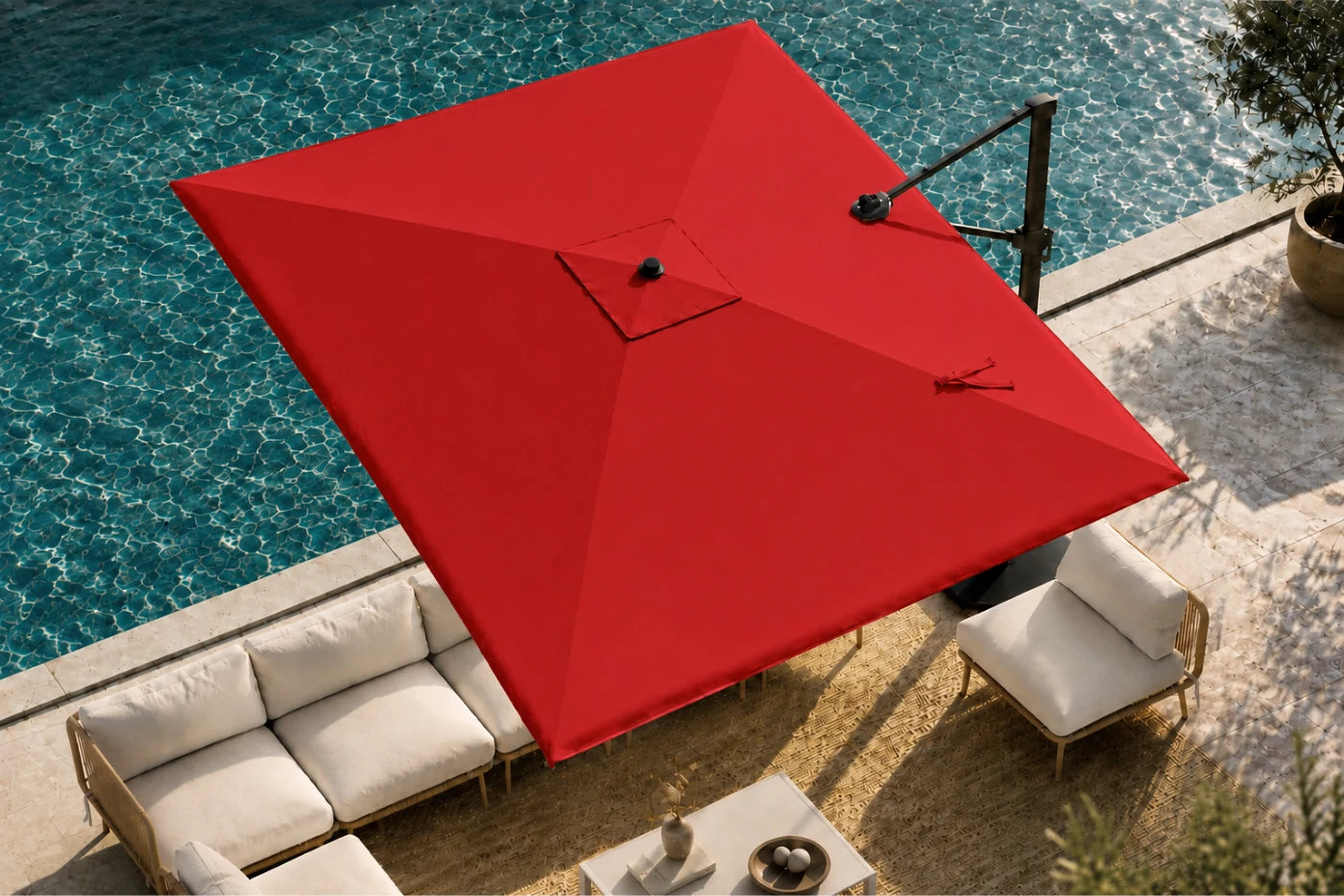 A large red patio umbrella with a cantilever arm, positioned over a modern outdoor lounge setup next to a swimming pool.